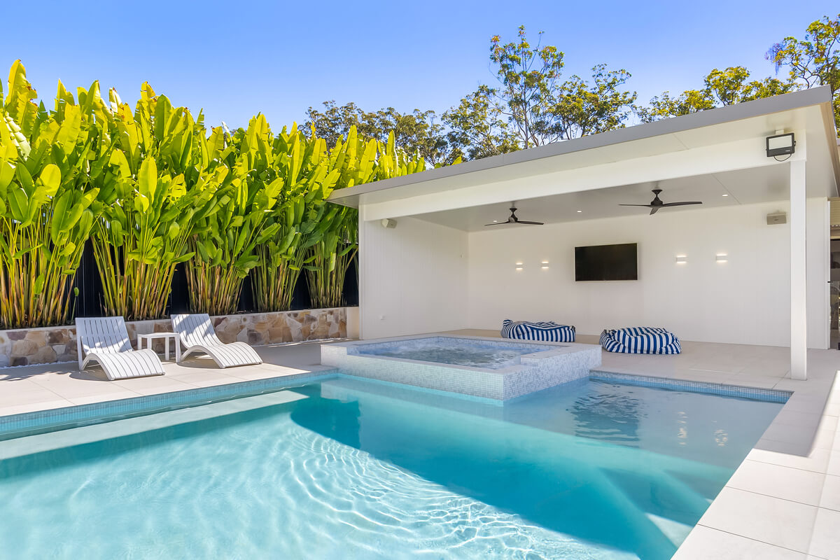 Modern outdoor pool with lounge chairs and shaded seating area.