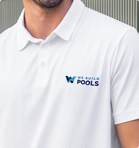 Person wearing a white polo shirt with 'We Build Pools' logo for pool construction.