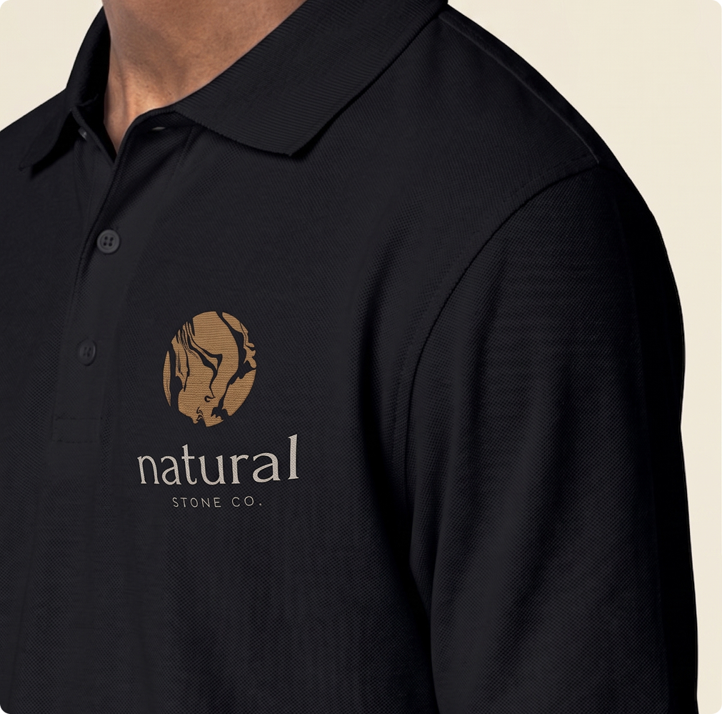 Natural Stone Co. logo on black polo shirt, close-up view.